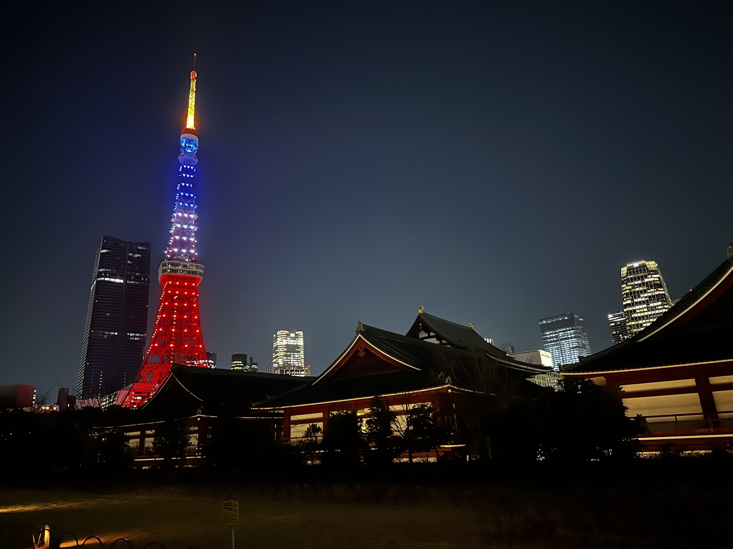 Tokyo Tower lit up at night with a shrine on the foreground.